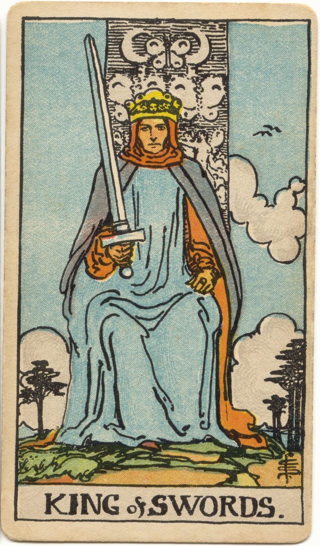 King of Swords: The sword held slightly off true, the direct gaze, the throne with butterflies and crescents, the crown and hood. Rider–Waite–Smith tarot, 1909.